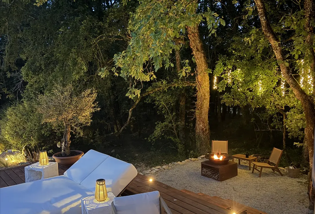 La terrasse du Zôme éclairée aux lanternes, le soir, sous les chênes