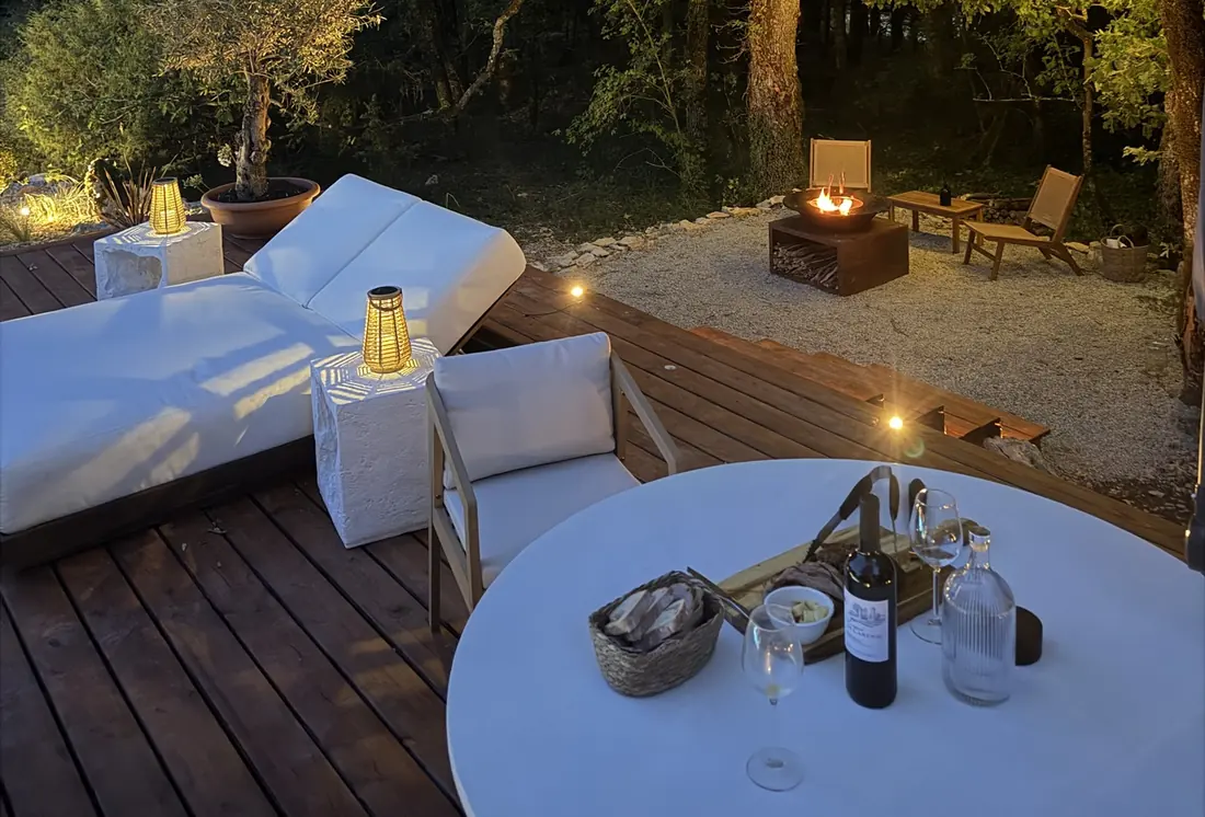 La table dressée pour deux sur la terrasse, le soir, à la lumière des lanternes