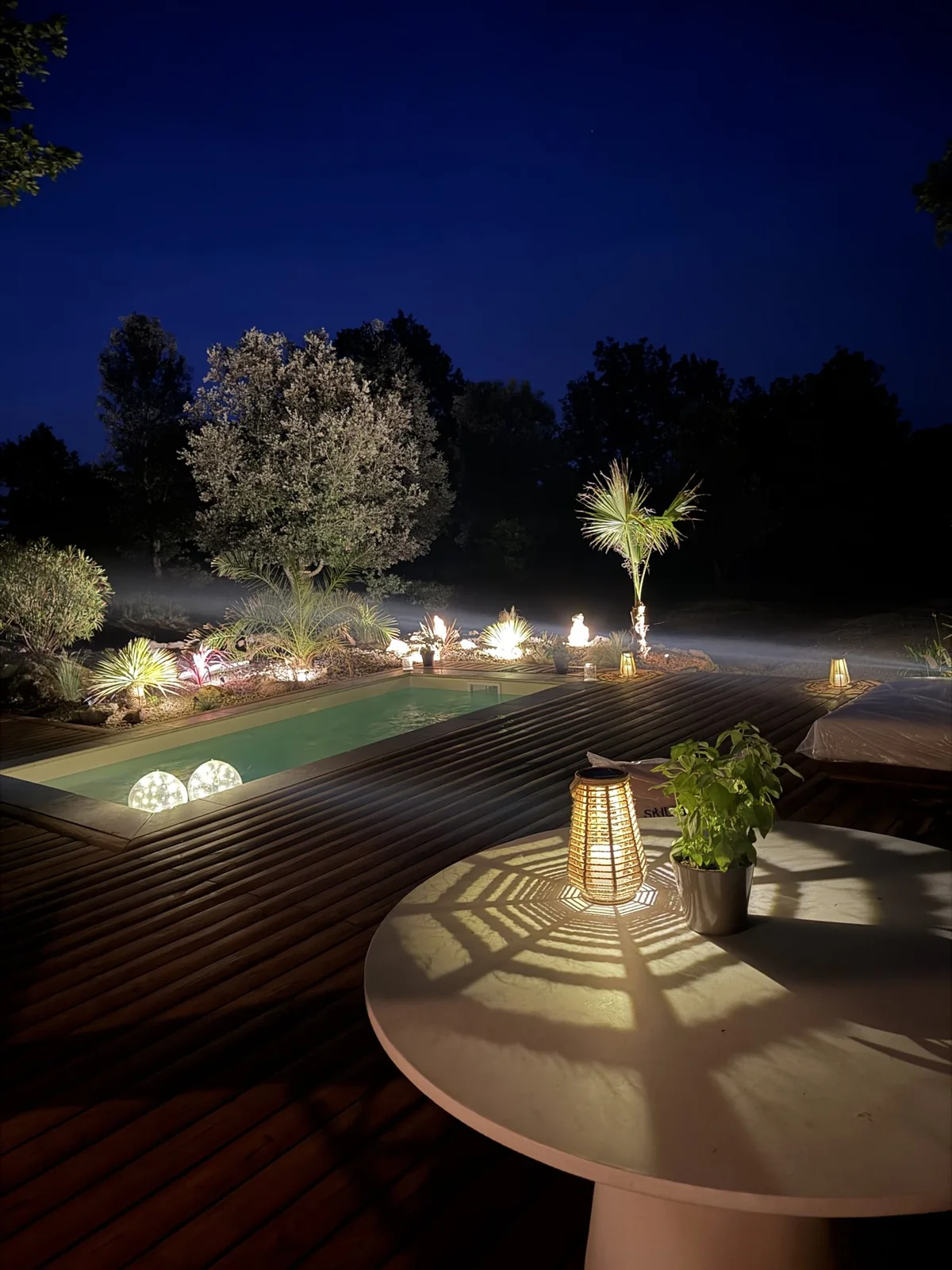 La piscine chauffée et une lanterne sur la terrasse, à la nuit tombée